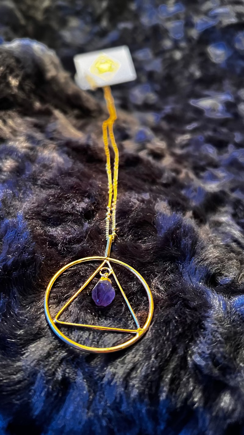 Necklace with a gold triangle pendant on a dark textured background