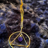 Necklace with a gold triangle pendant on a dark textured background