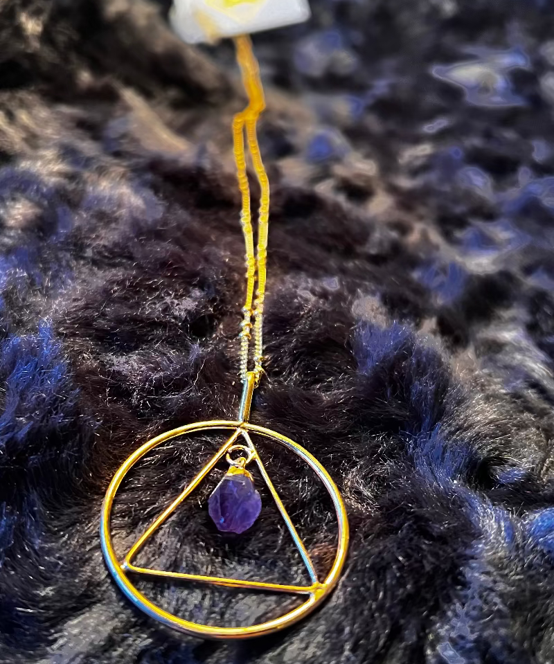 Necklace with a gold triangle pendant on a dark textured background