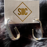 Silver earring on a card with 'SUC' logo against a fur background