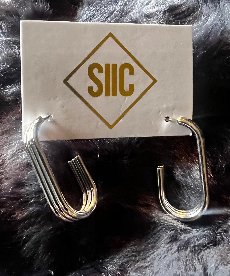 Silver earring on a card with 'SUC' logo against a fur background