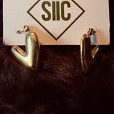Gold heart-shaped earrings on a card with 'SIIC' logo against a dark background