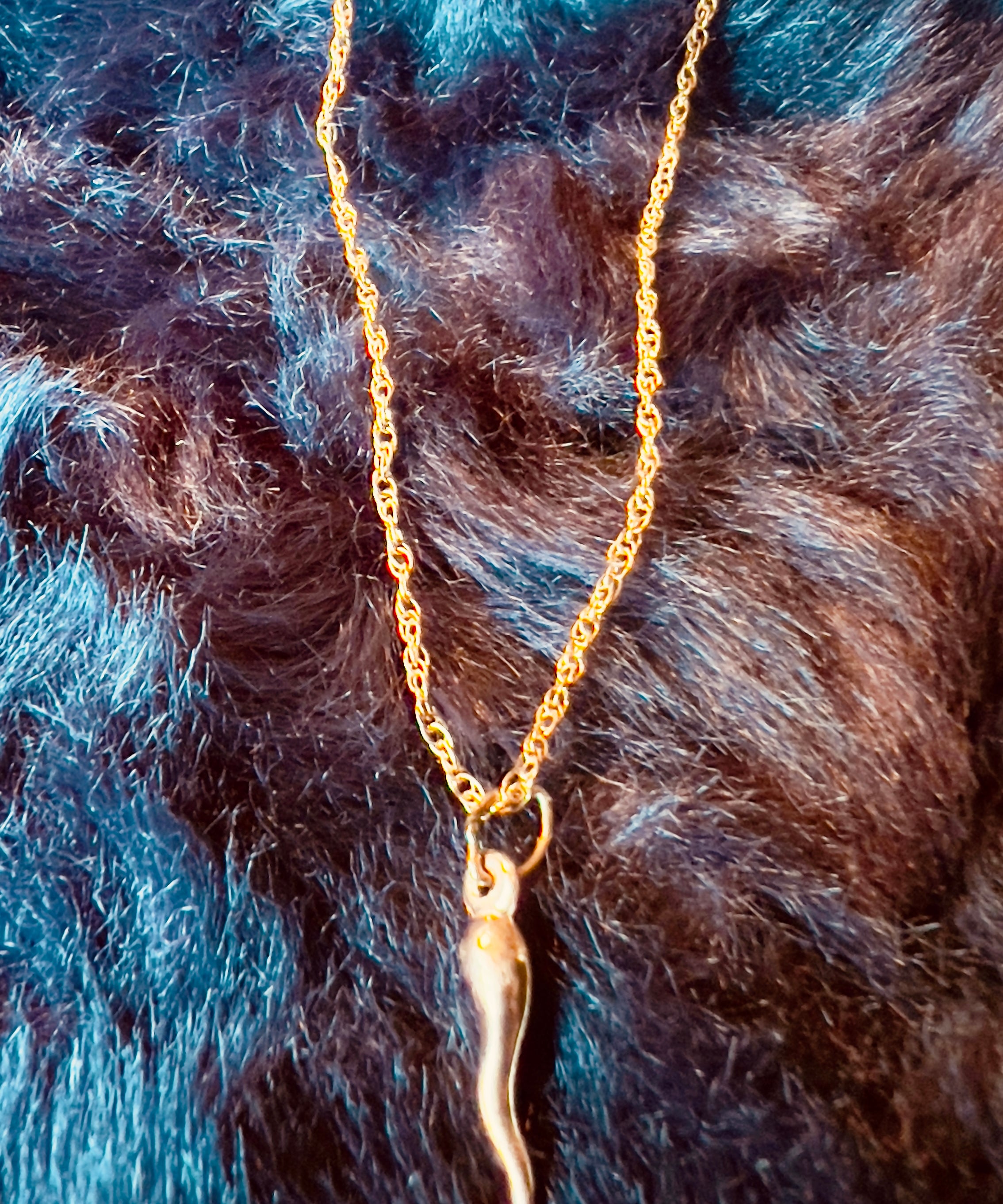 Gold necklace with a pendant on a fur background