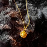 Gold necklace with a sunflower pendant on a black fur background
