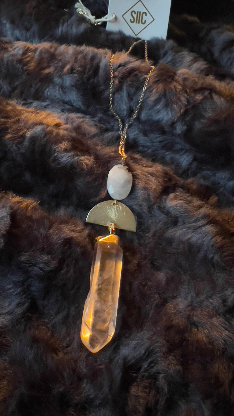 necklace with a gold and beige pendant on a dark fur background