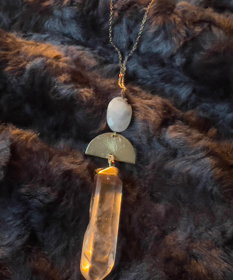 necklace with a gold and beige pendant on a dark fur background