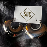 Silver hoop earrings on a black fur background with 'SIIC' card.