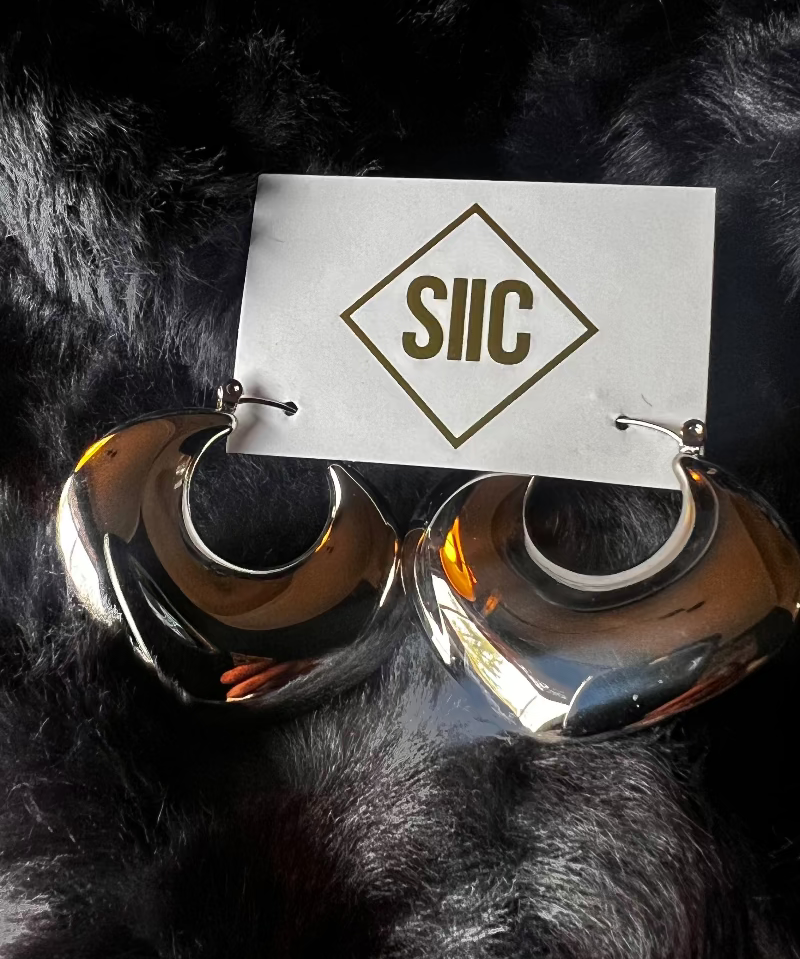 Silver hoop earrings on a black fur background with 'SIIC' card.