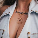 Close-up of a person wearing a gold necklace with a pendant, showing a tattoo on the neck wearing Soul Sister since 1969.