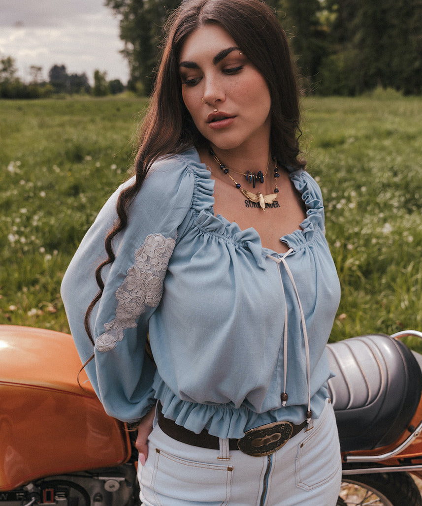 Woman standing next to a motorcycle in a field wearing Soul Sister since 1969