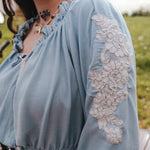 Light blue peasant blouse with lace sleeves worn by a person in an outdoor setting clothing by Soul Sister since 1969