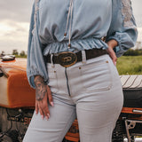 Person wearing a light blue top and sun faded denim bell bottom jeans designed by Soul Sister since 1969 standing next to a vintage motorcycle.