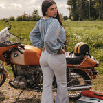 Woman standing next to a vintage motorcycle in a field wearing Soul Sister since 1969