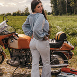 Woman standing next to a vintage motorcycle in a field wearing Soul Sister since 1969