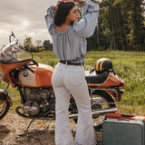 Woman standing next to a motorcycle in a field with a suitcase nearby wearing a sweet Jane peasant blouse by Soul Sister since 1969