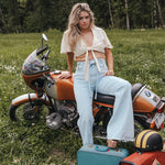 Woman sitting on a motorcycle with suitcases in a grassy field Soul Sister since 1969.