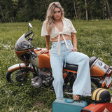 Woman sitting on a motorcycle with suitcases in a grassy field Soul Sister since 1969.
