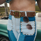 Person wearing a blue shirt and white pants with a brown belt and sunglasses, standing next to a vintage car Wearing Soul Sister since 1969. 