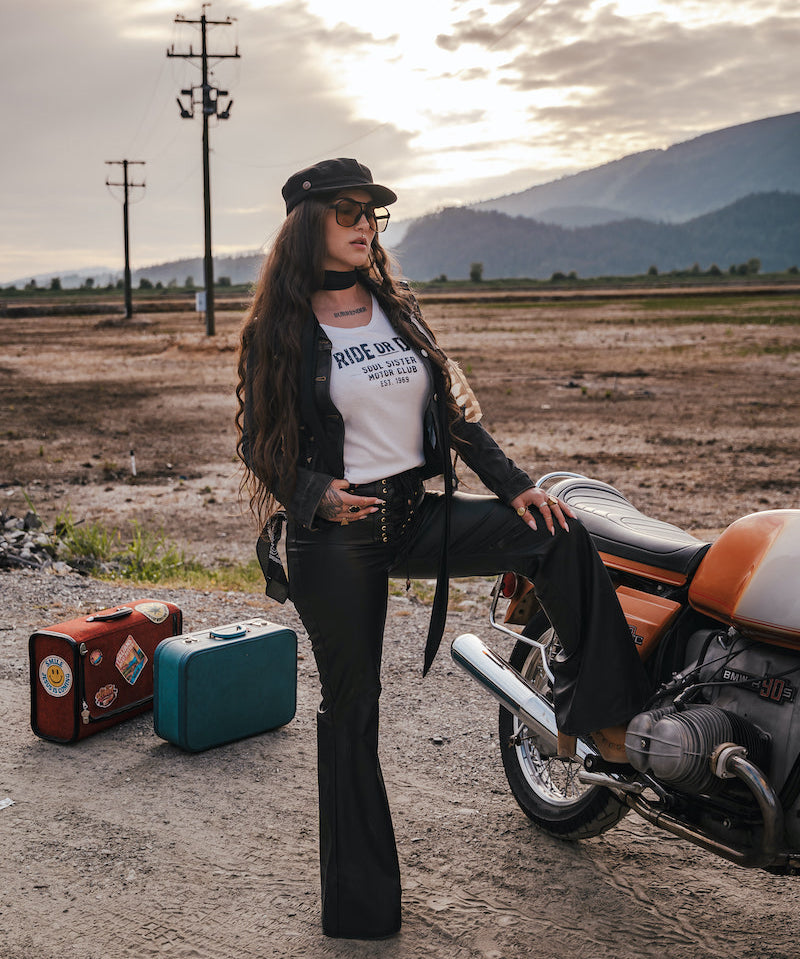 Woman in a desert setting with a motorcycle and suitcases, wearing a 'Ride or Die' t-shirt designed and made by Soul Sister since 1969.