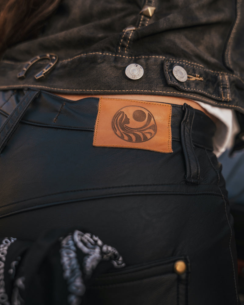 Close-up of a dark jacket with a leather patch featuring a logo wearing clothing designed and made by Soul Sister since 1969..