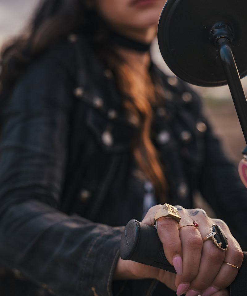 Person wearing multiple rings on a motorcycle, with a microphone close-up wearing Soul Sister since 1969.