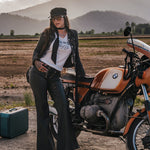 Woman standing next to a motorcycle in a desert landscape with mountains in the background wearing Soul Sister since 1969