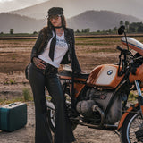 Woman standing next to a motorcycle in a desert landscape with mountains in the background wearing clothing designed and made by Soul Sister since 1969.
