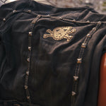 Black leather jacket with gold skull emblem and studs on a blurred background wearing Soul Sister since 1969