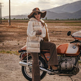 Person sitting on a motorcycle in a desert-like setting with mountains in the background wearing Soul Sister since 1969