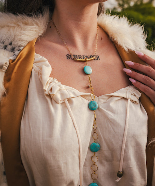 Person wearing a necklace with turquoise stones and a tattoo on their chest wearing soul sister since 1969.