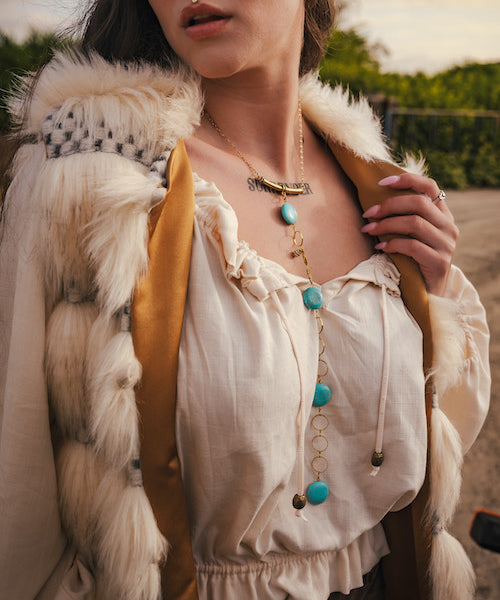 Person wearing a fur vest and white blouse with accessories outdoors wearing soul sister since 1969