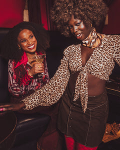 afro queen rocks a 70s look in a bar with a friend
