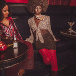 Two women sitting on a couch in a bar setting with drinks and decor.