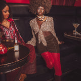 Two women sitting on a couch in a bar setting with drinks and decor.