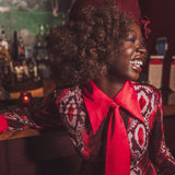 Woman in a stylish outfit with a red scarf and patterned jacket in a bar setting
