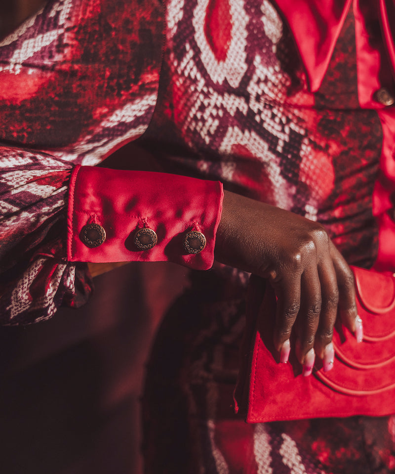 Close-up of a person wearing a red and black patterned garment with a focus on the sleeve and hand.
