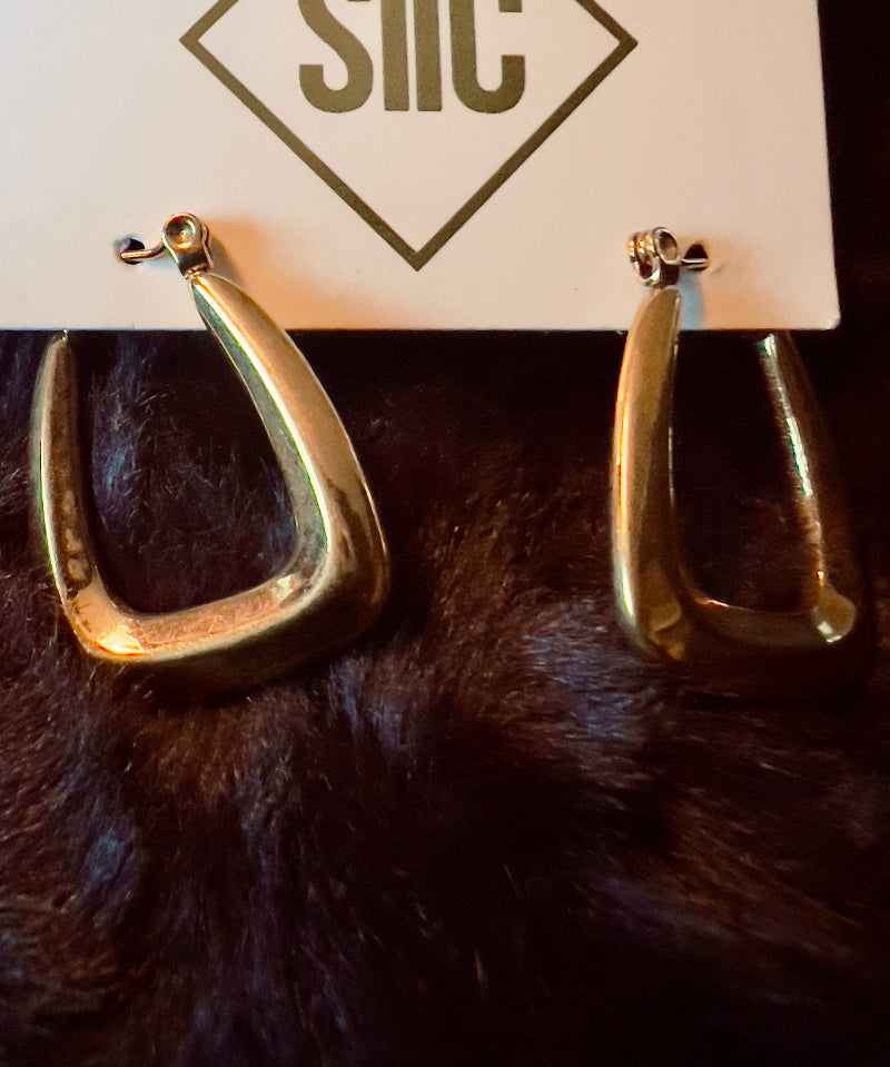Gold hoop earrings on a card with 'SIIC' branding, displayed on a dark fur surface.