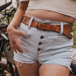 Person wearing light blue denim shorts with a studded belt, standing next to a motorcycle wearing Soul Sister since 1969..