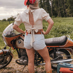 Person standing next to a motorcycle in a field with a red bandana and open back top wearing Soul Sister since 1969..