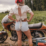 Person standing next to a motorcycle in a field with a red bandana and open back top wearing Soul Sister since 1969..