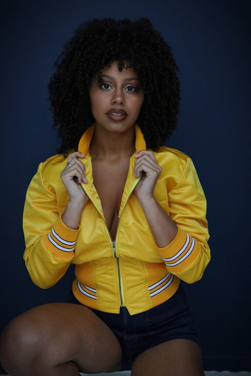 Surprised Black woman in bright 80s windbreaker jacket in yellow